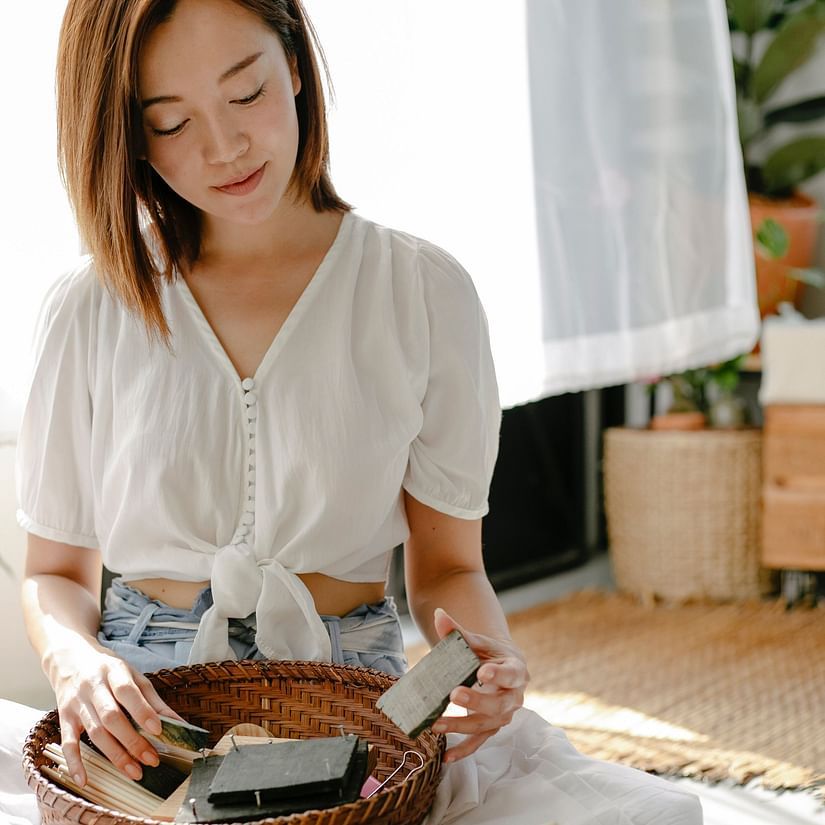 a woman holding a block print with other block prints in a basket