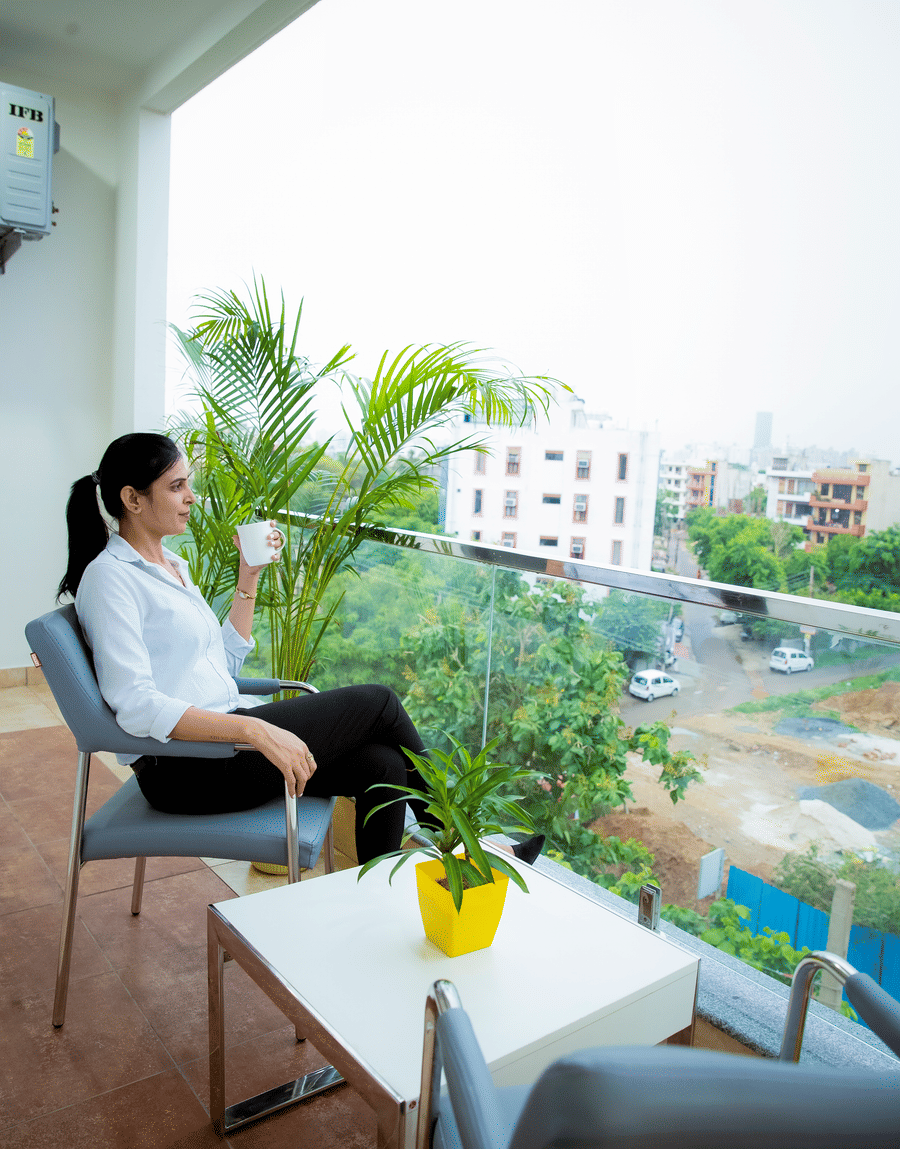 Guest relaxing on the balcony of the Standard Studio with Balcony, overlooking greenery, at Lime Tree Luxury Studio