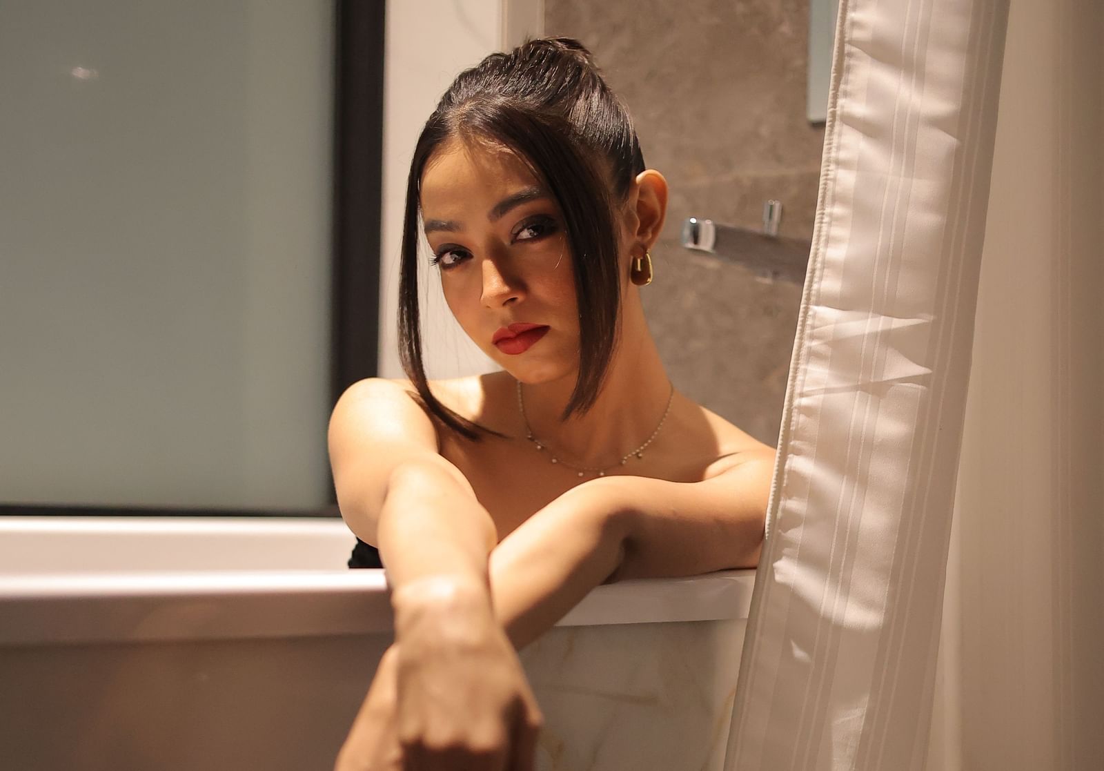 A woman posing gracefully in a bathtub available in one of our accommodations in Agartala - Polo Hotel Agartala