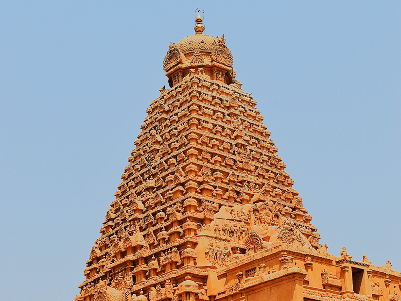 Tall, pyramid-shaped stone gopuram tower of a majestic South Indian temple under a clear sky.