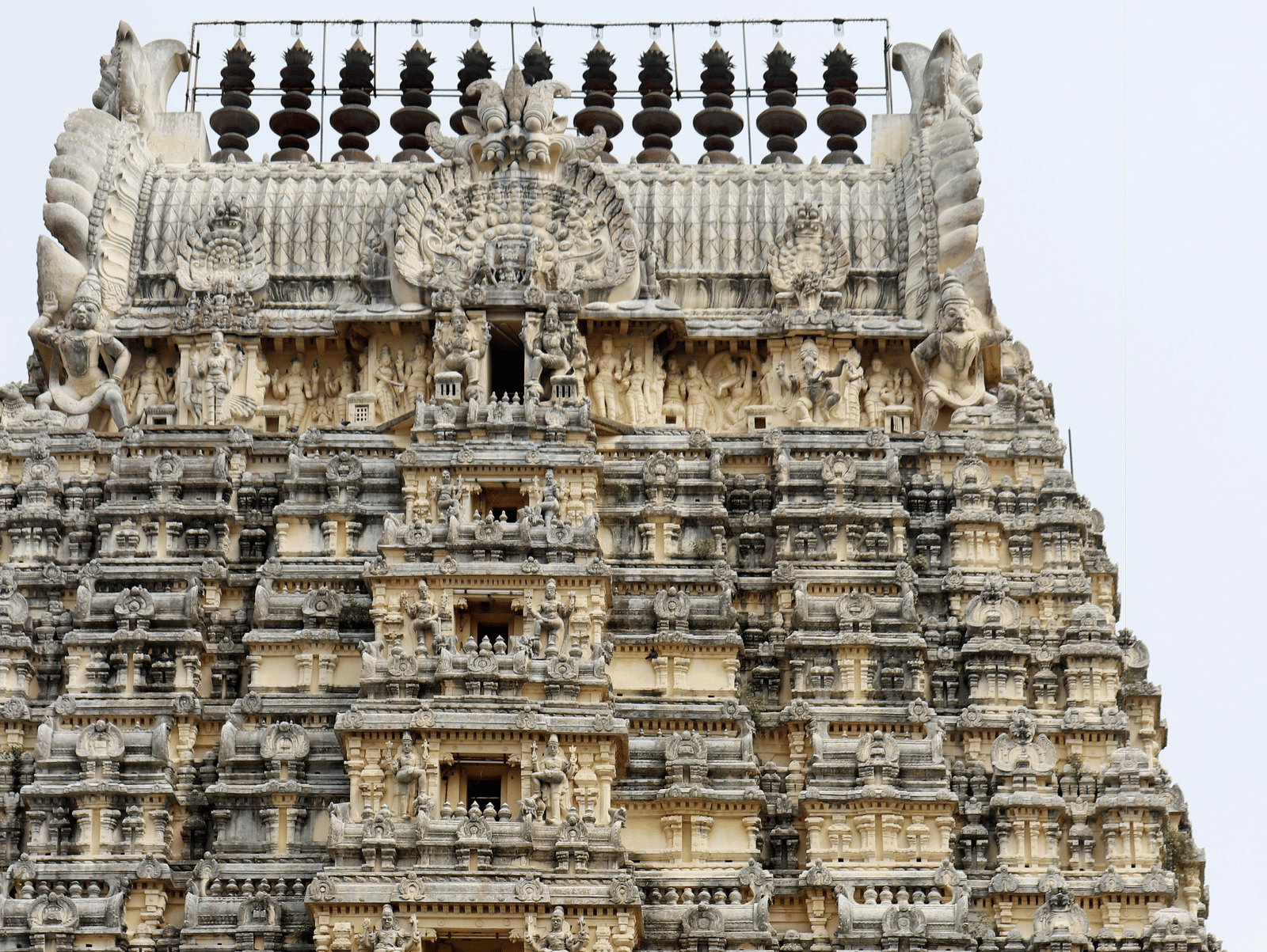 Stone-carved temple tower (gopuram) with intricate sculptures and detailed architectural design, typical of South Indian temples.Stone-carved temple tower (gopuram) with intricate sculptures and detailed architectural design, typical of South Indian temple