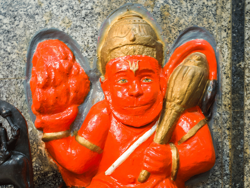 An idol of Lord Hanuman holding the mace and partially kneeling on one knee