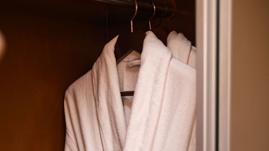 a close up image of a white bathrobe hanging inside a closet - The Claridges New Delhi