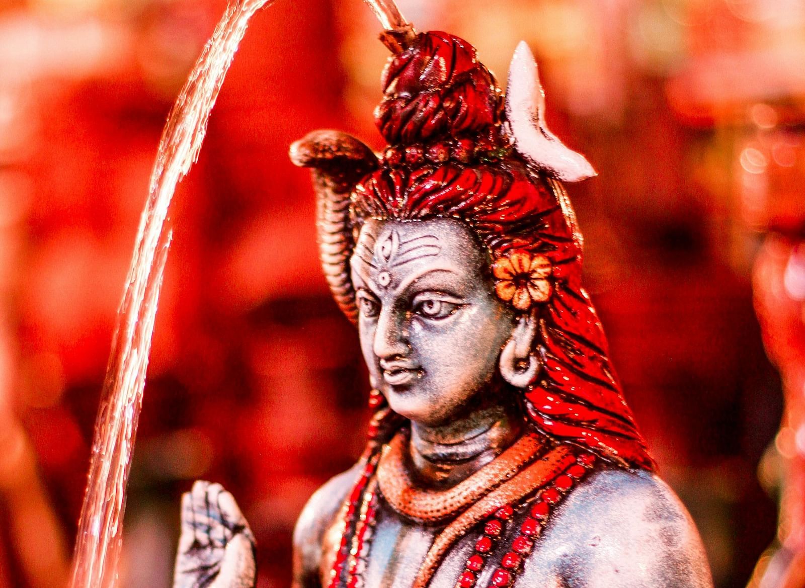  A vibrant statue of Lord Shiva, painted in red tones, highlighting the divine figure.