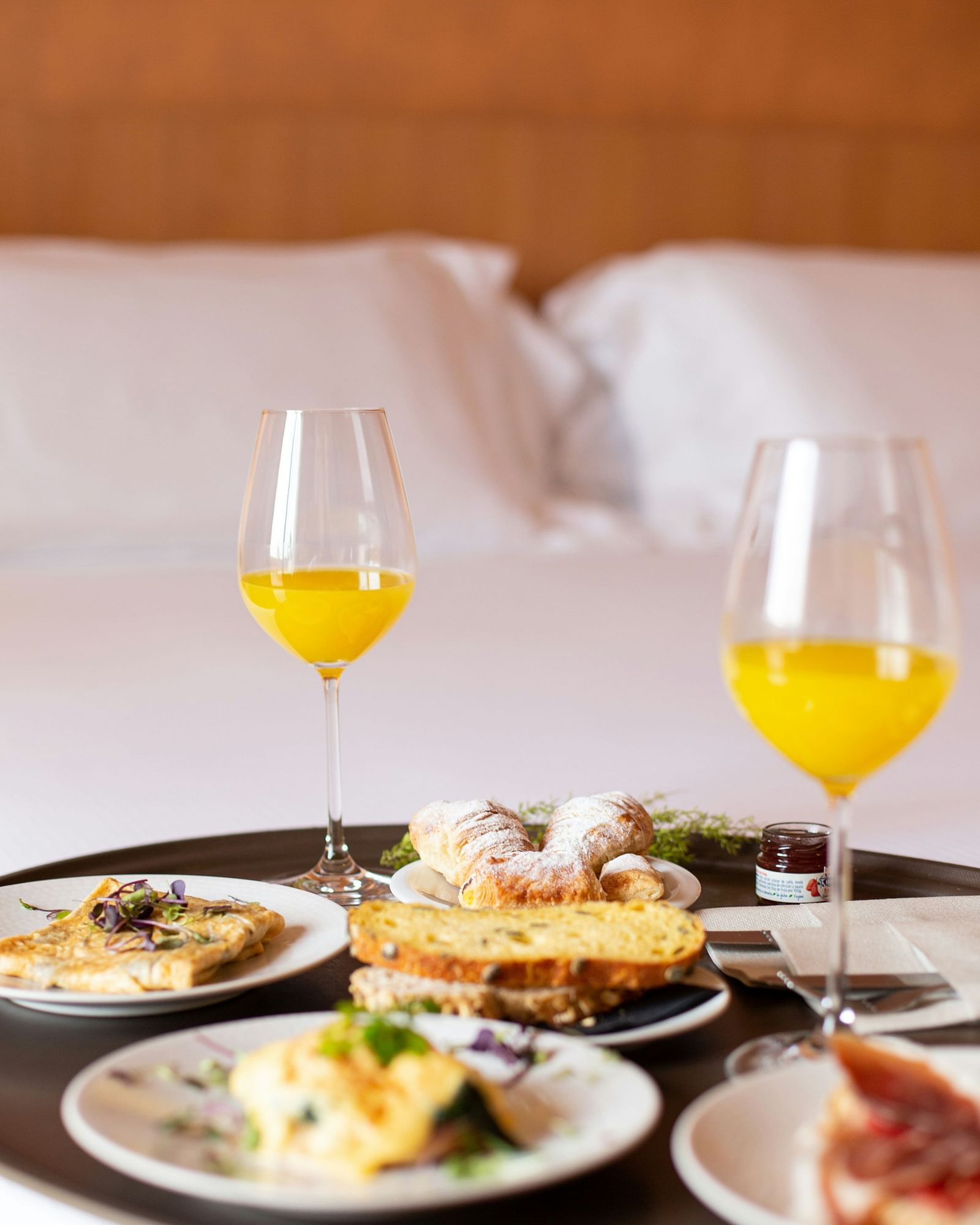 Breakfast in bed with juice and assorted dishes on a tray