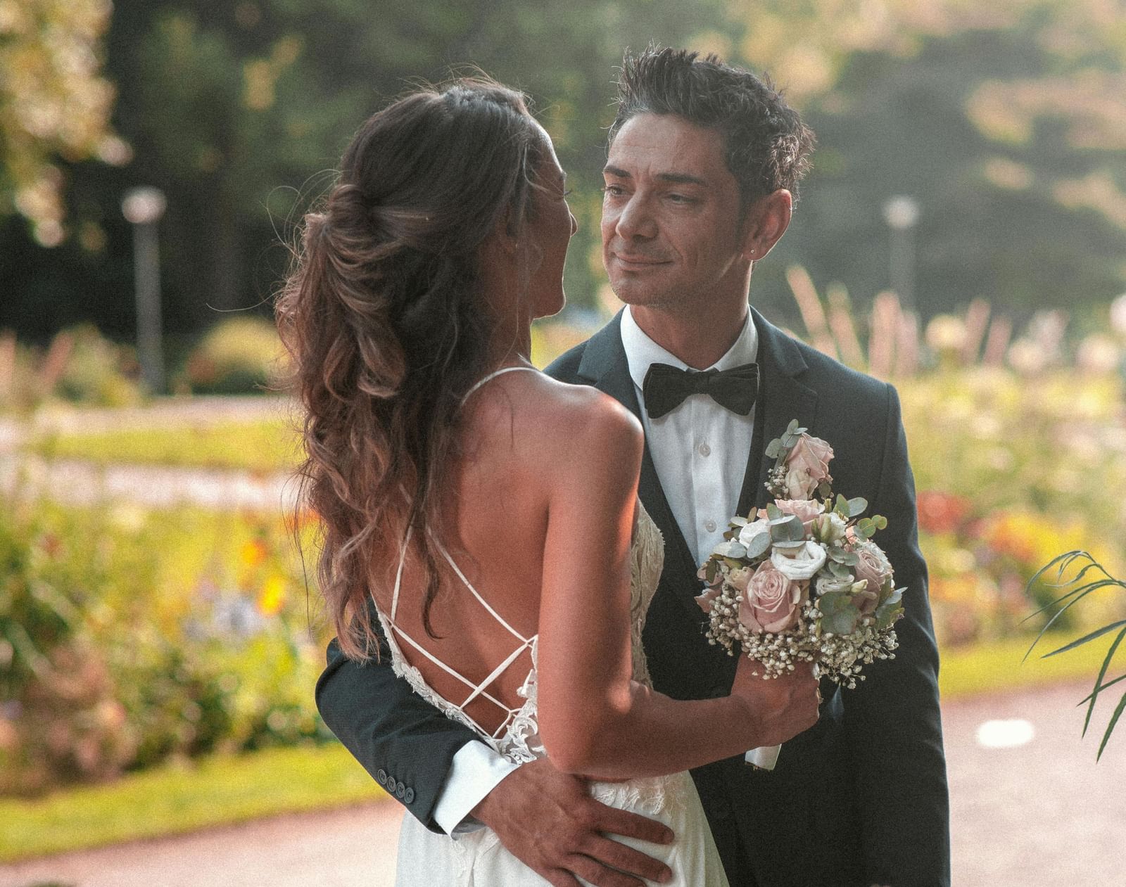 A bride and a groom posing for a photo with flowers in the foreground