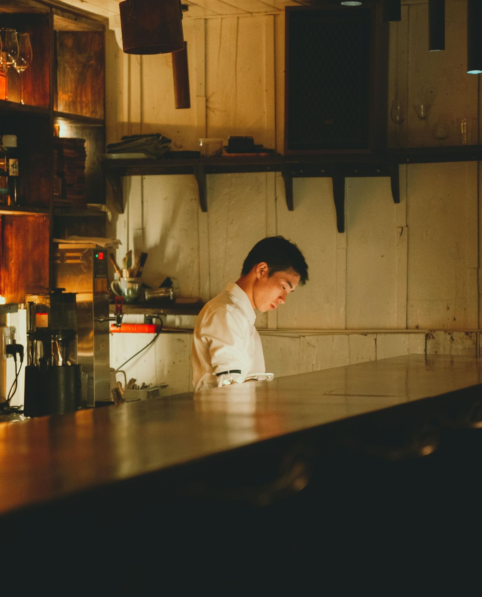 An image of a chef behind a kitchen counter in a dimly lit kitchen