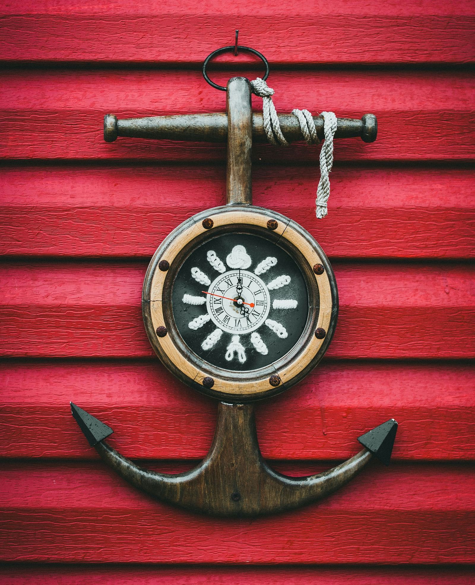 A ship anchor is mounted on a red wall with a compass