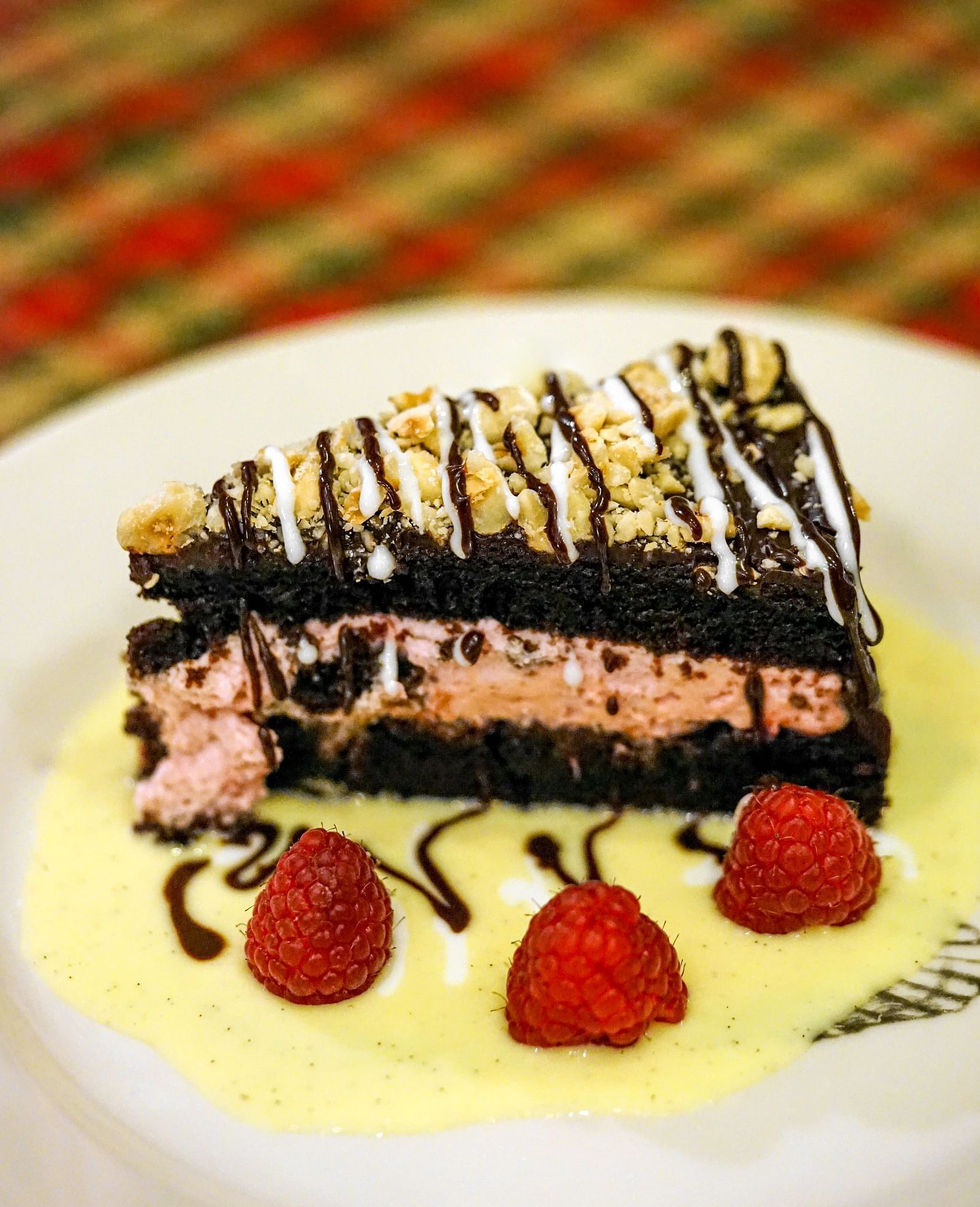 Close-up of a decadent chocolate cake topped with raspberries and a creamy sauce - Brewery Gulch Inn & Spa