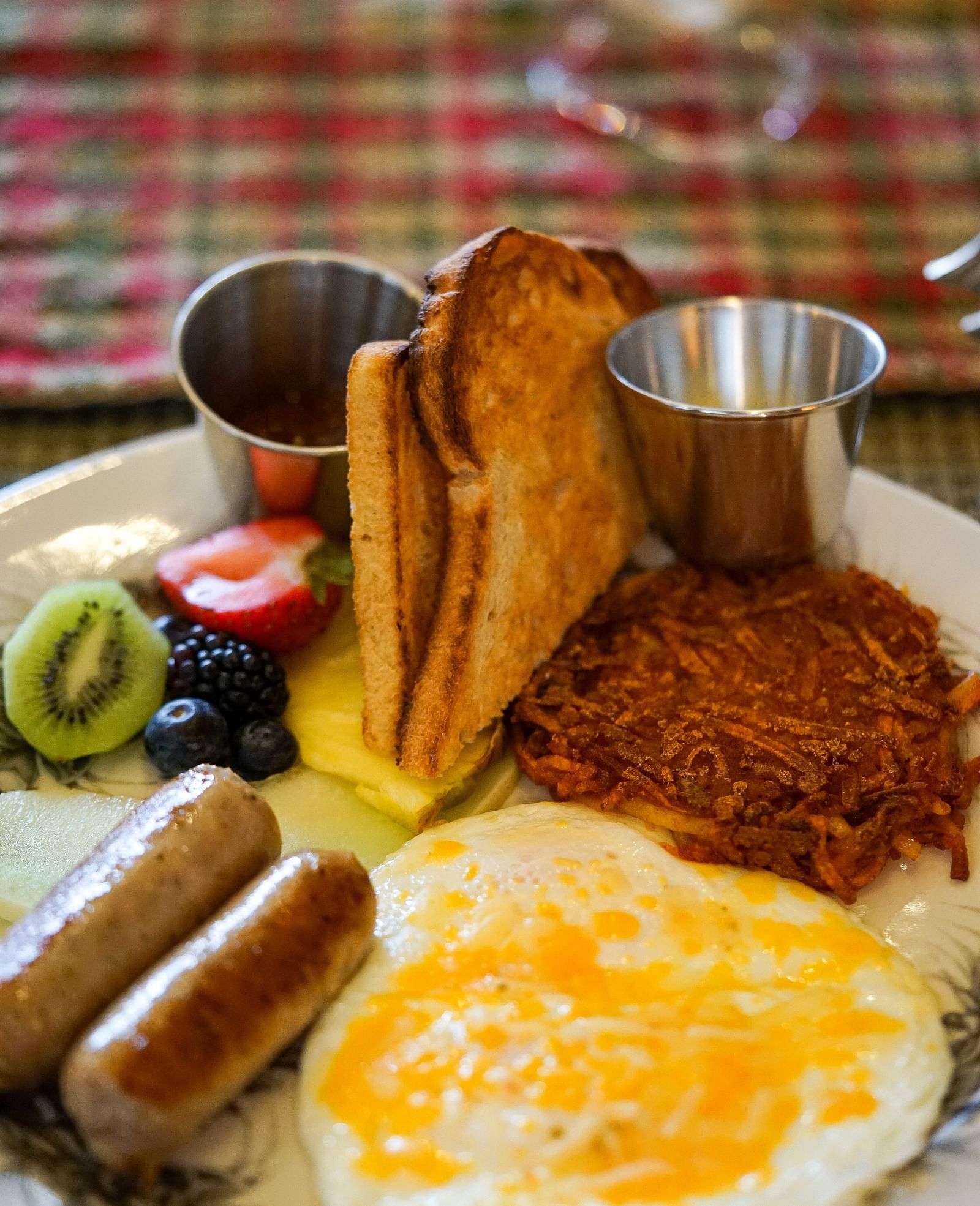 A wholesome breakfast plate with scrambled eggs, toasted bread, grilled sausage, and fresh fruit - Brewery Gulch Inn & Spa