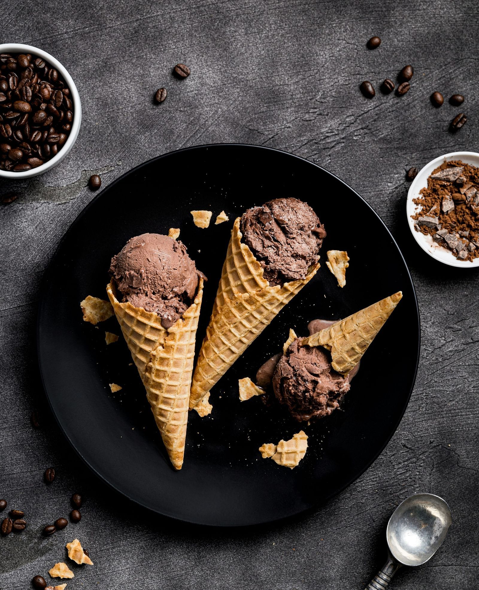 3 chocolate ice cream cones placed on a black plate.