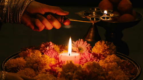 A platter with flowers, a candle being presented to a god by a woman
