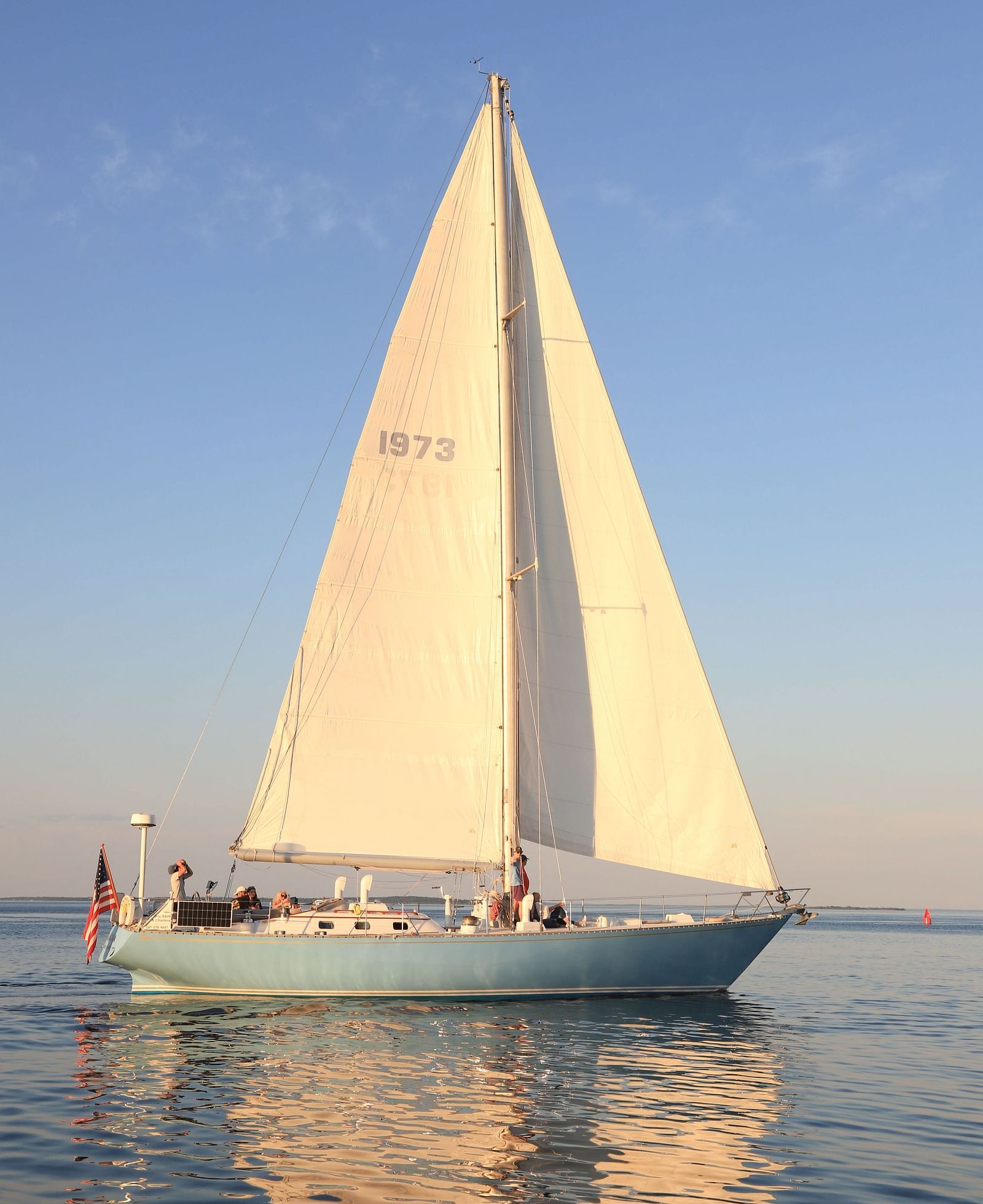 White sailboat gliding on calm waters at sunset near Hartstone Inn.