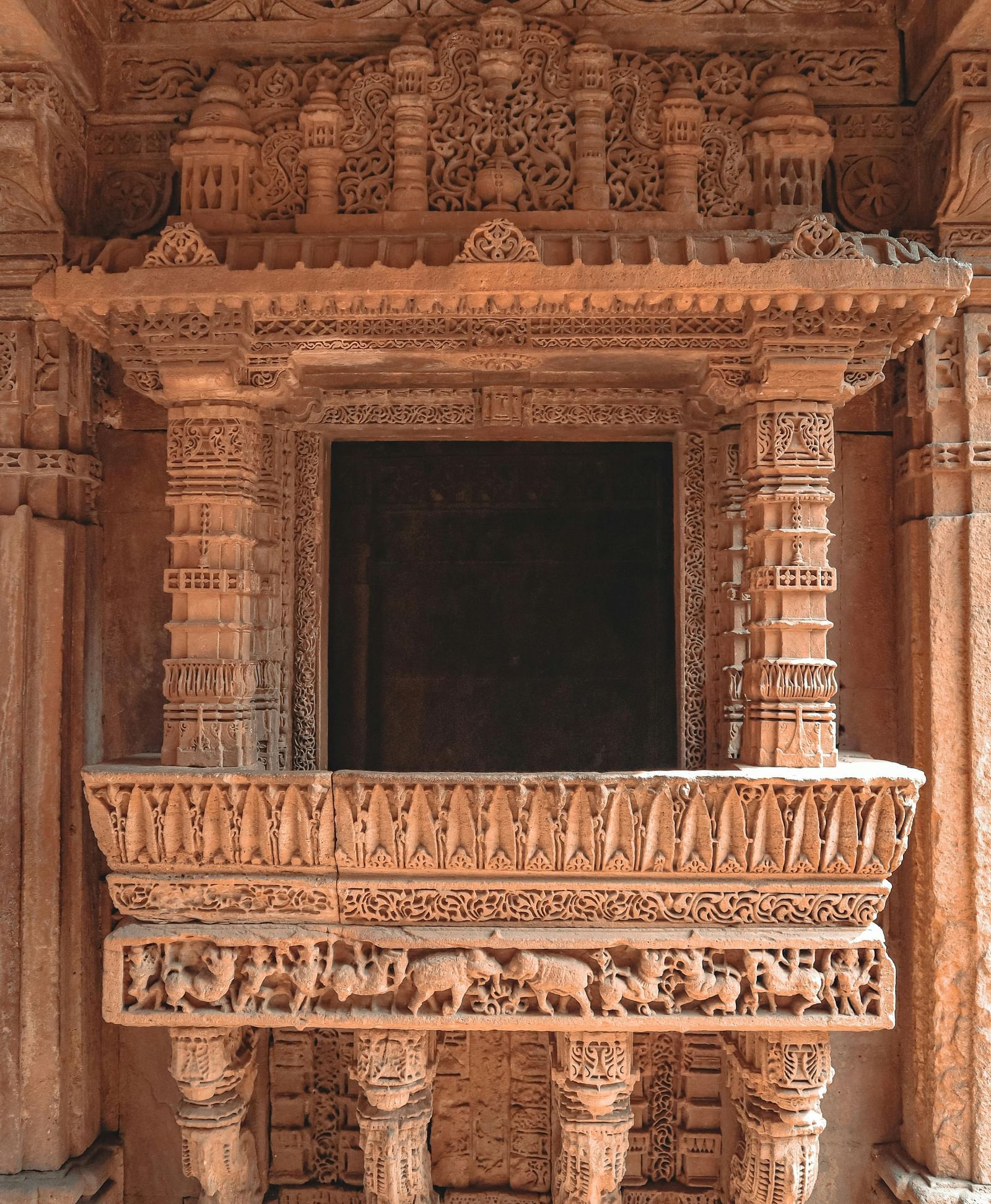 An ancient balcony with ornate stone carvings in a classical Indian architectural style