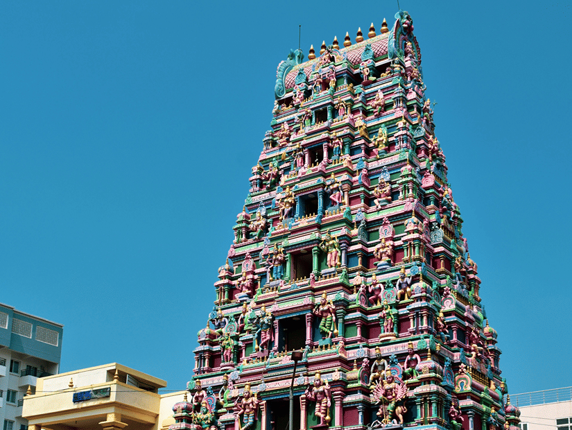 A view from outside of a South Indian temple with carvings of deities on the the gopurams, symbolising Perur Pateeswarar Temple, one of the Coimbatore tourist places to visit.