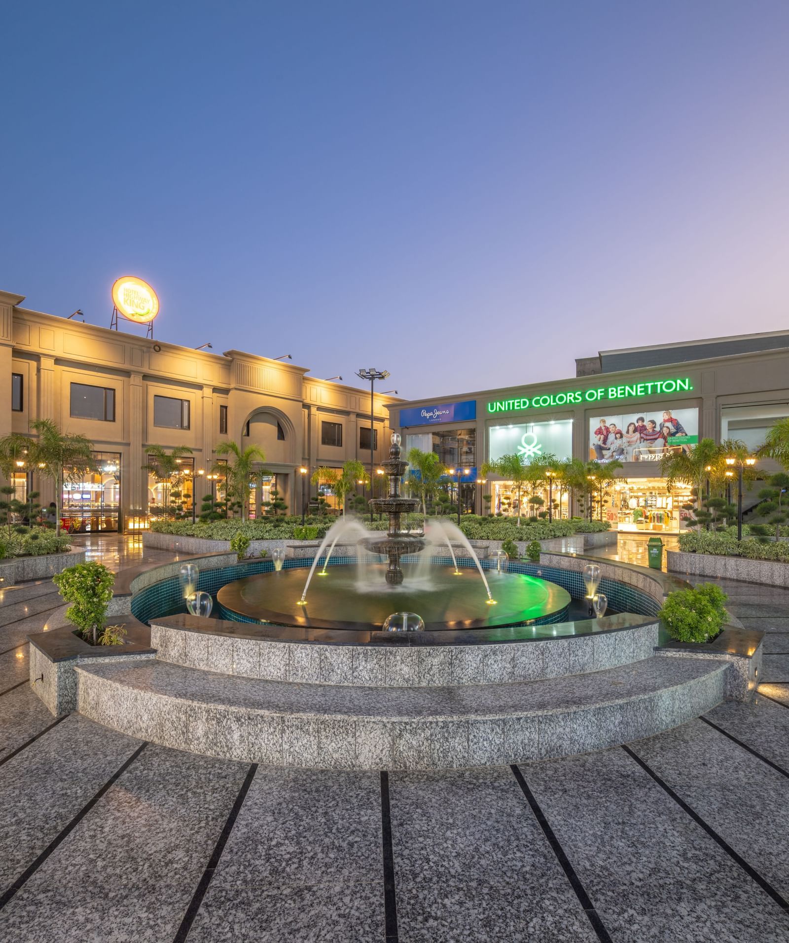 Main entrance view with central fountain at Hotel Highway King, Kishangarh lit during dusk.