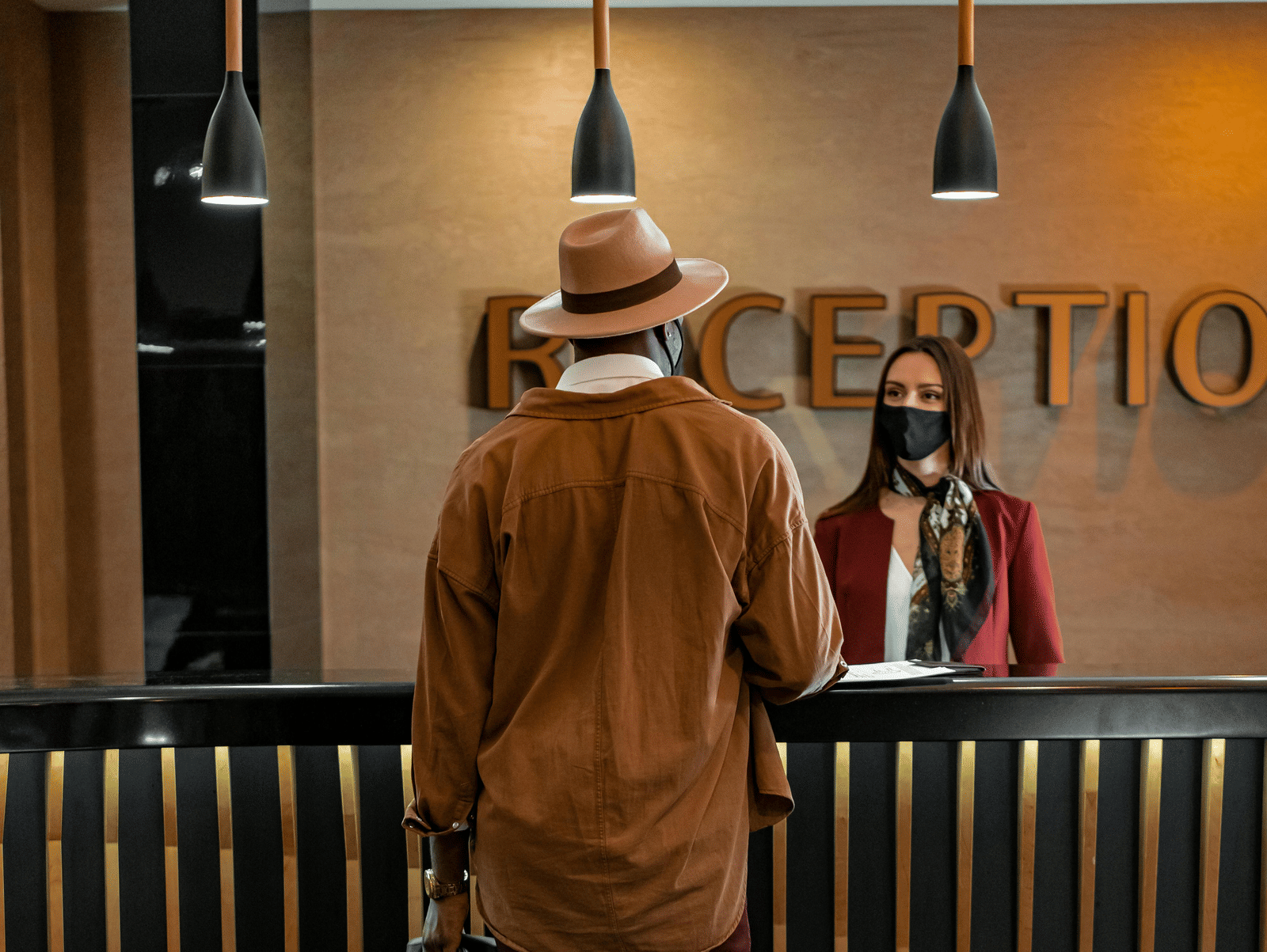 A person conversing with a receptionist to check in to a hotel.