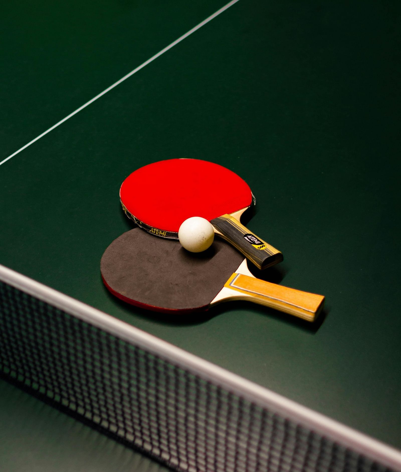 A pair of table tennis bats and a ball placed on the table tennis table