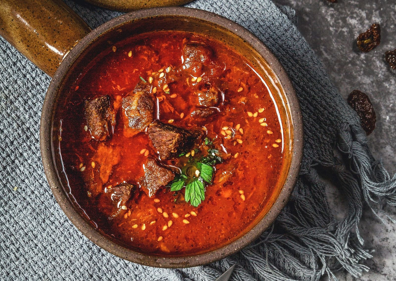 An aerial view of a lamb curry kept inside a bowl and placed on a table.
