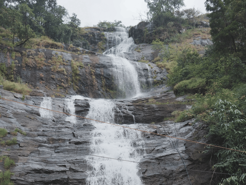 A waterfall surrounded by rocky mountains and green trees.