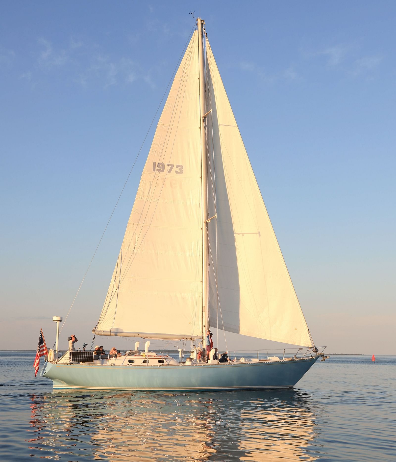 White sailboat gliding on calm waters at sunset near Hartstone Inn.
