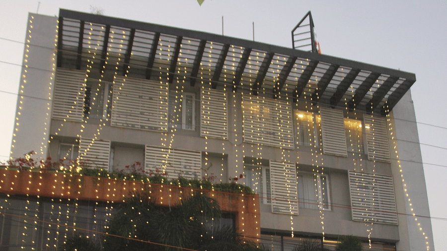 The facade of the multi-storey Pipul Padmaja Premium Hotel & Convention with lights and cars parked in the front.