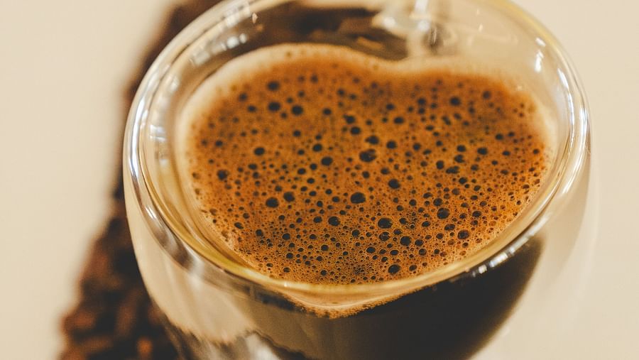 An image of  a cup of coffee and on one side coffee beans are placed - The Garden Ananta Elite, Rajkot 