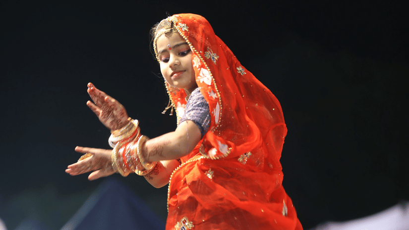 A woman dressed in chaniya choli playing garba bare feet during the night.
