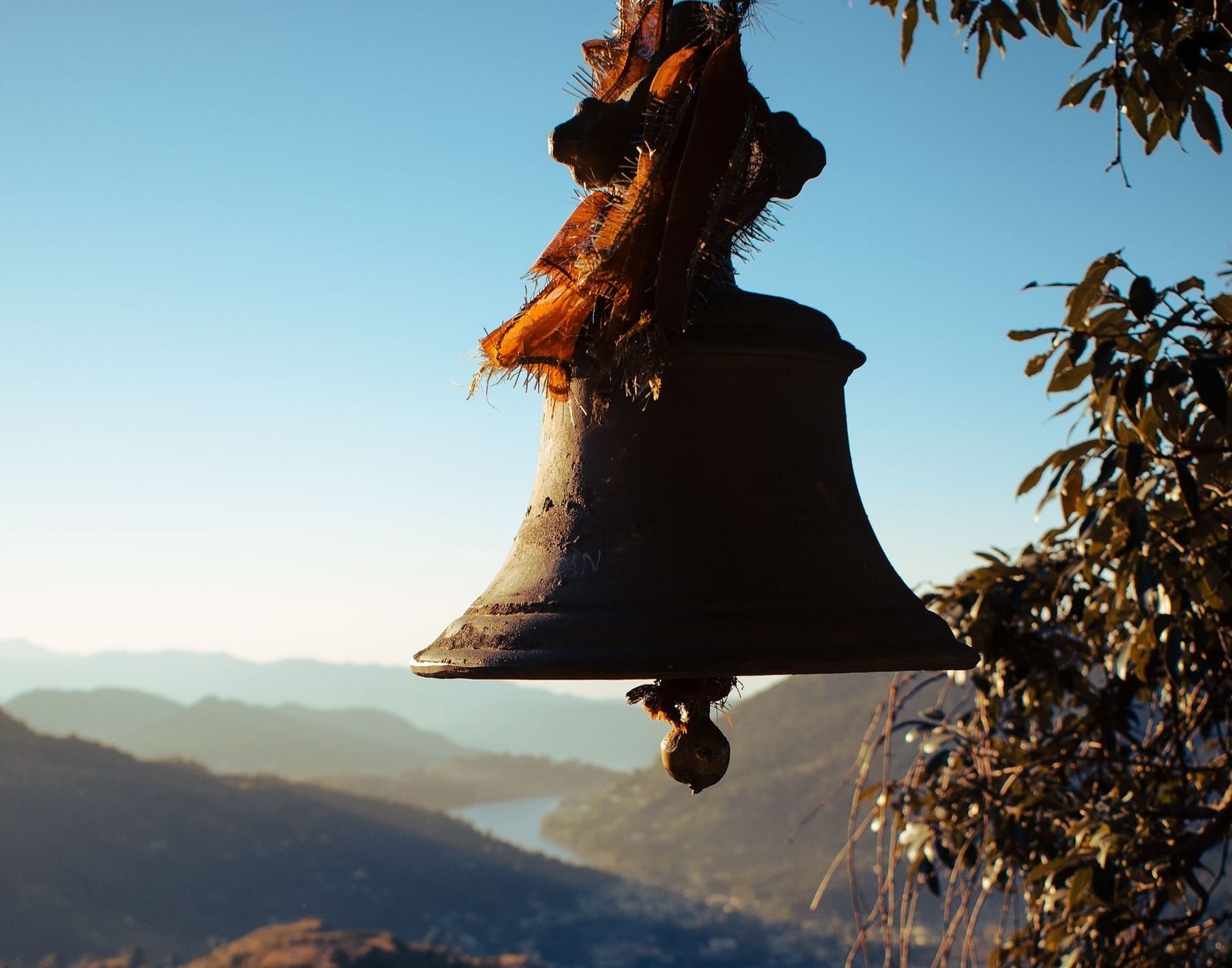 a close up shot of a bell with a valley in the background