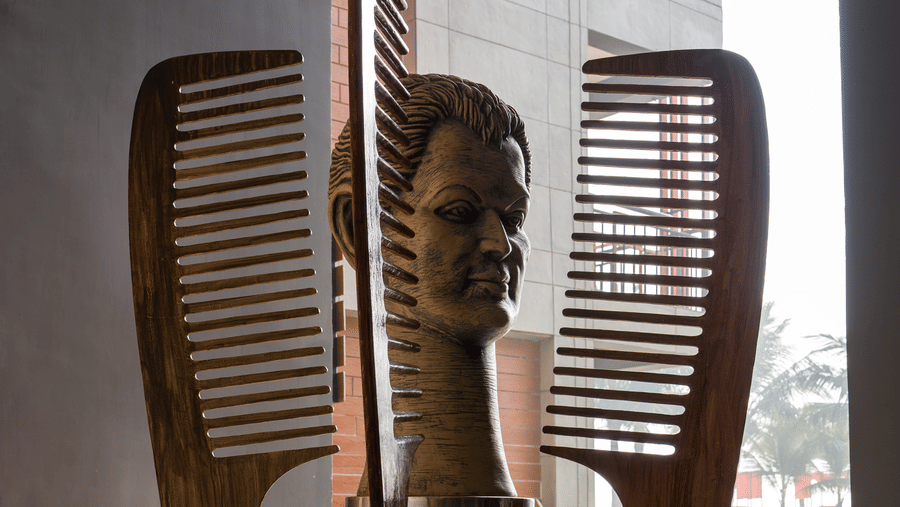 Decorative wooden sculpture of a bust and 2 large combs around it displayed at Hotel Sonar Bangla, Taki.