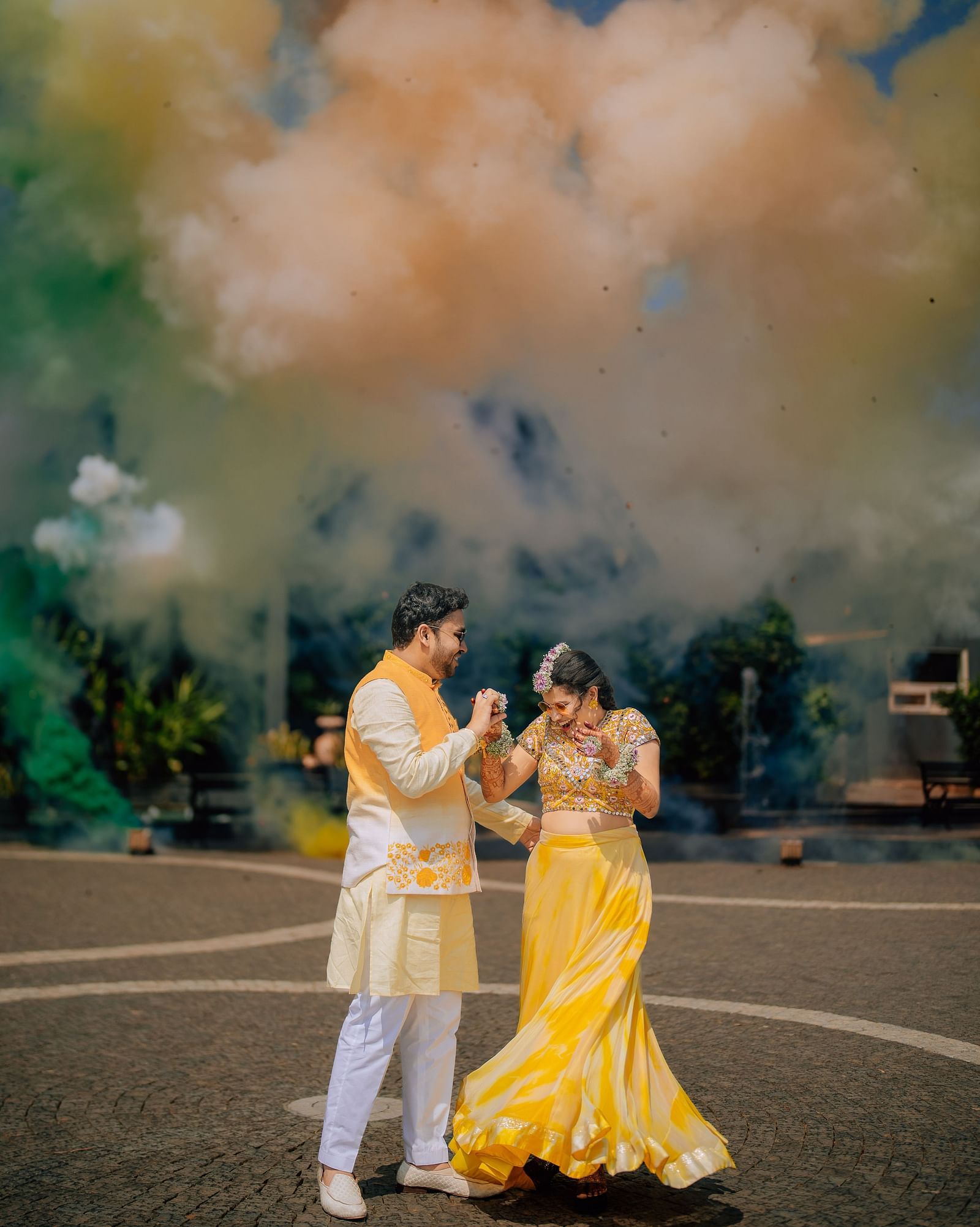 image of the couple standing close to each other at darza resorts with colour bombs exploding in the background