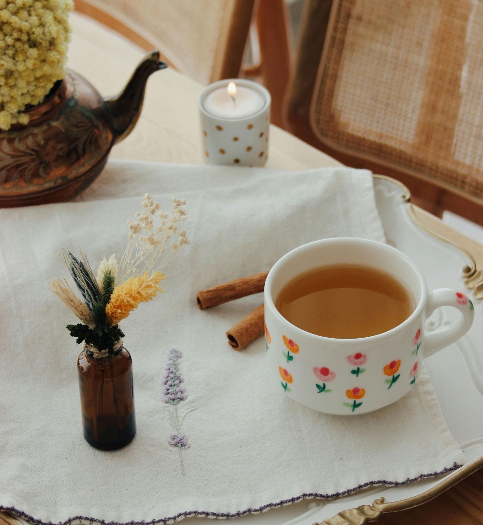A beautifully arranged tray with a cup of tea, essential oils, and a flower vase on a table. | Mango Hill, Yercaud