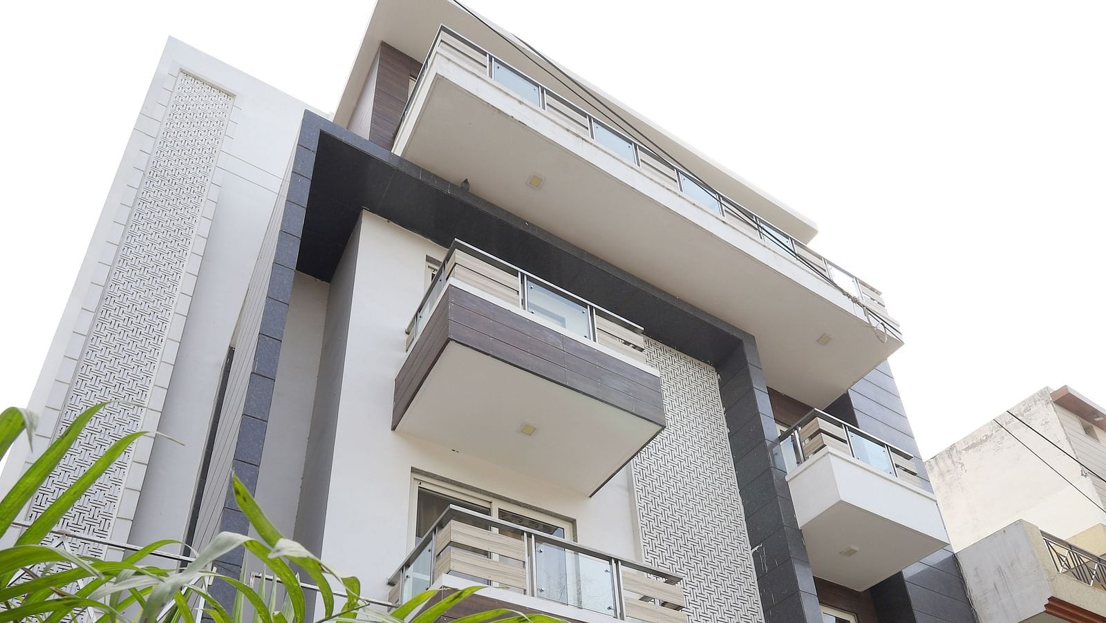 An exterior shot of a contemporary building with angular design and greenery visible in the foreground - Asian Suites Cyber Park, Gurgaon