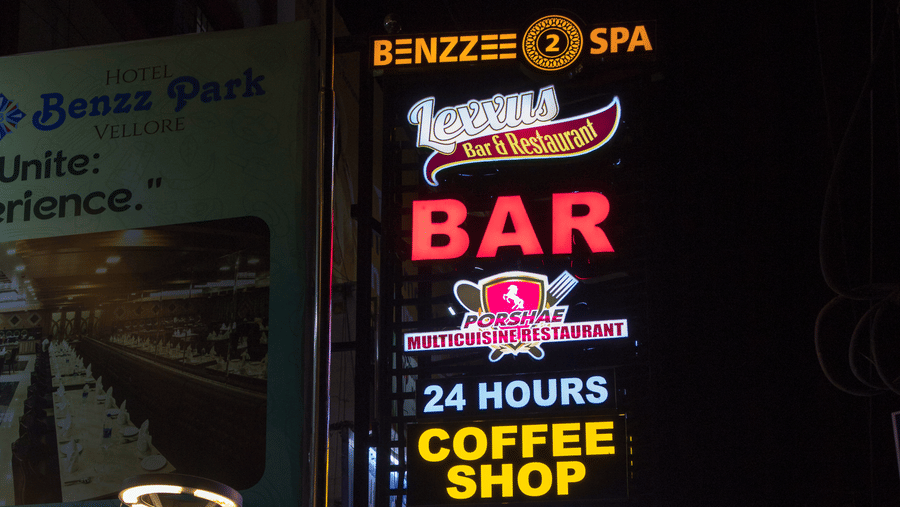 A neon signboard outside Benzz Park, Vellore, brightly lit during the night.