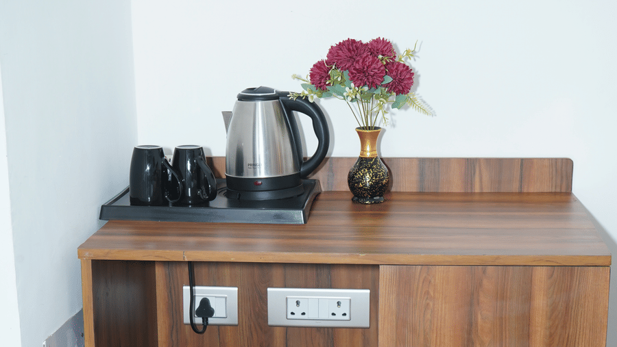 In-room tea and coffee maker station placed on a wooden console cabinet alongside mugs and a trash bin - Five Elements Hotels, Corbett Crown Resort, Jim Corbett