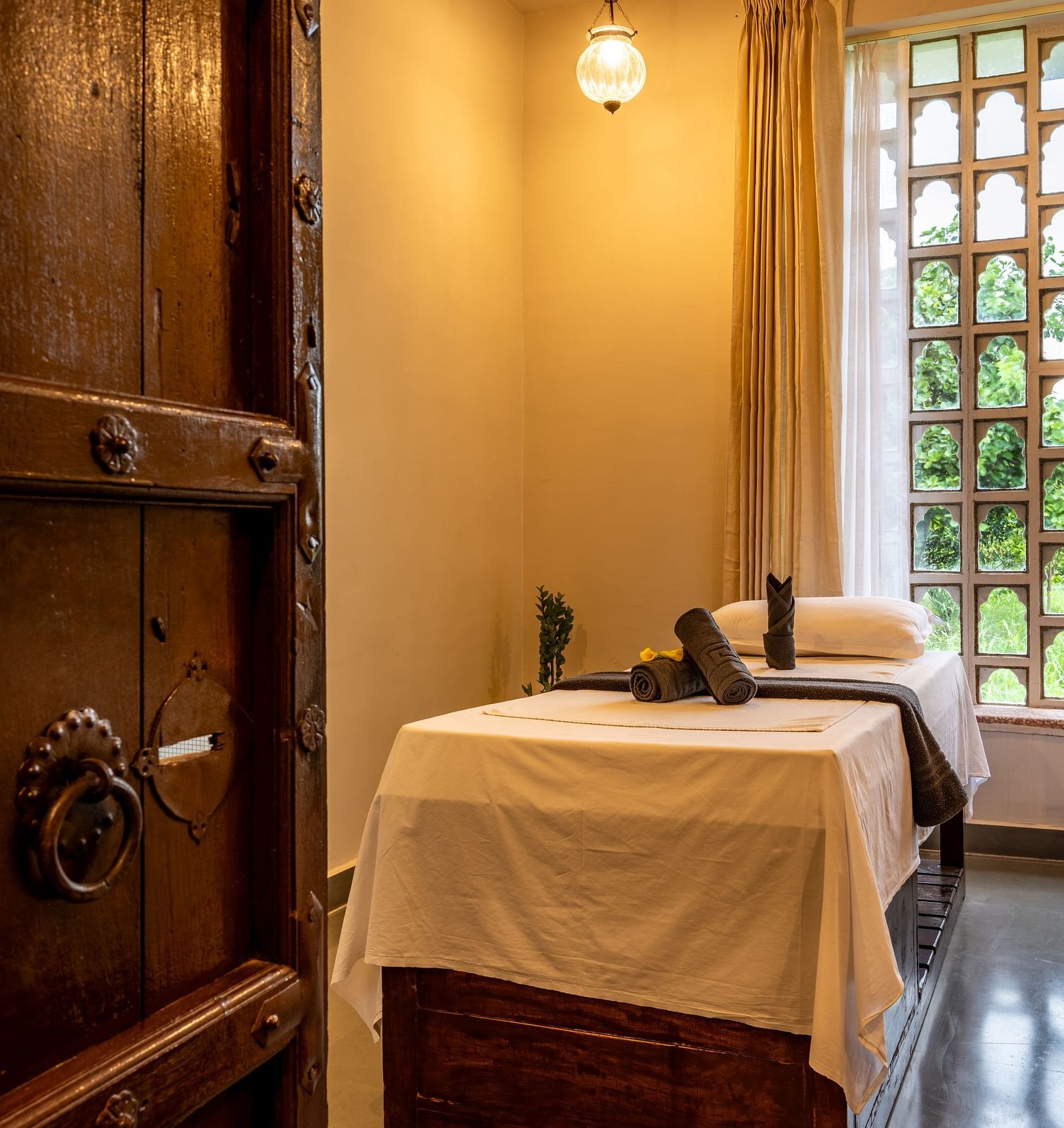 A wooden door opening to the spa with a bed and ambient lighting - Utsav Camp