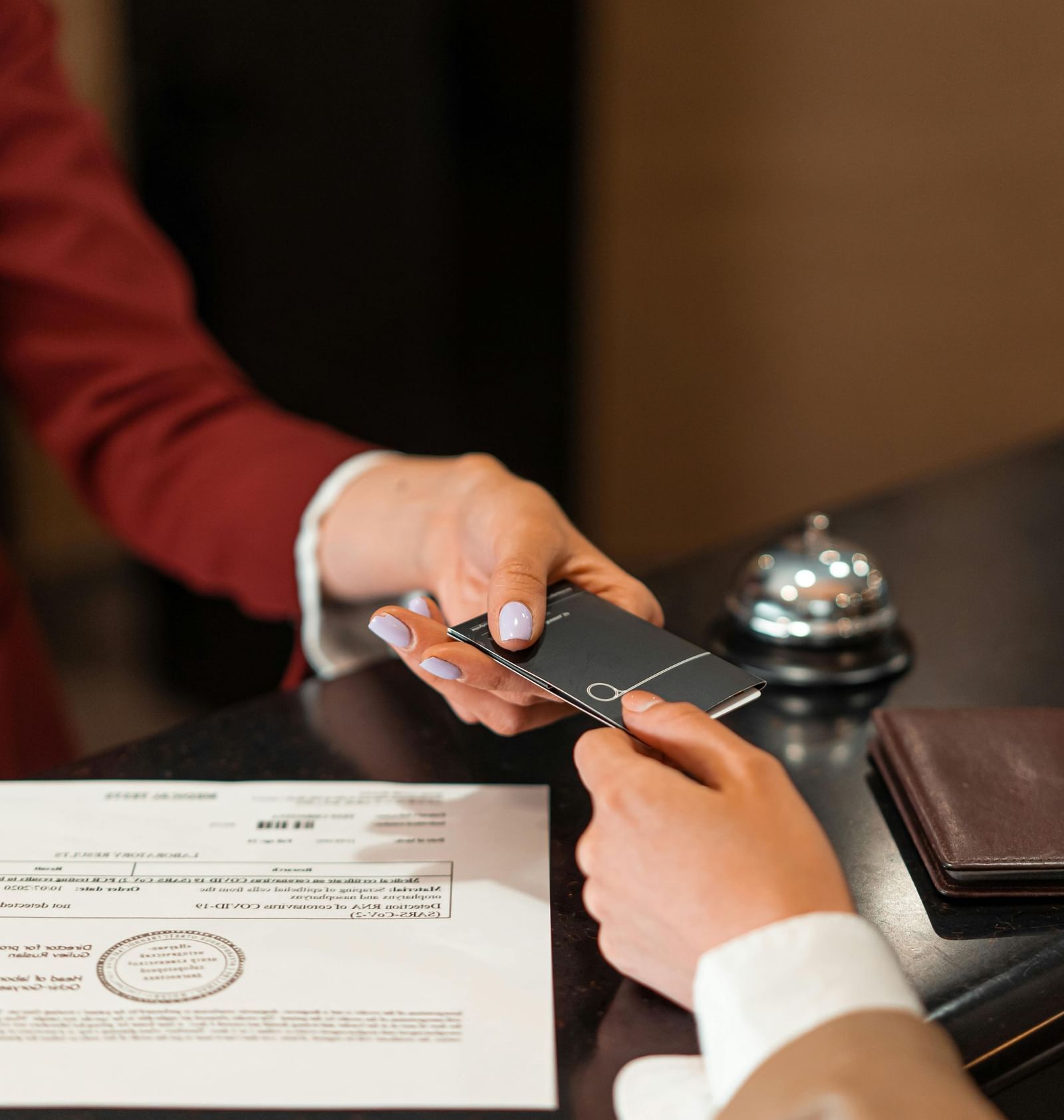 The receptionist handing over the key card to a guest over the front desk.