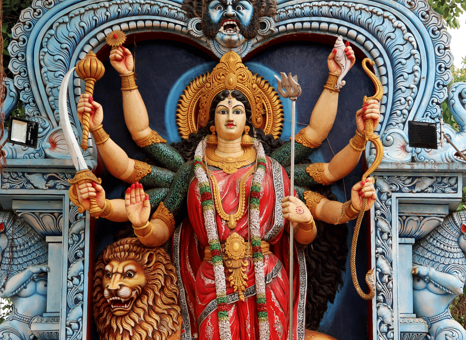 A statue of an Indian goddess with a lion behind her.