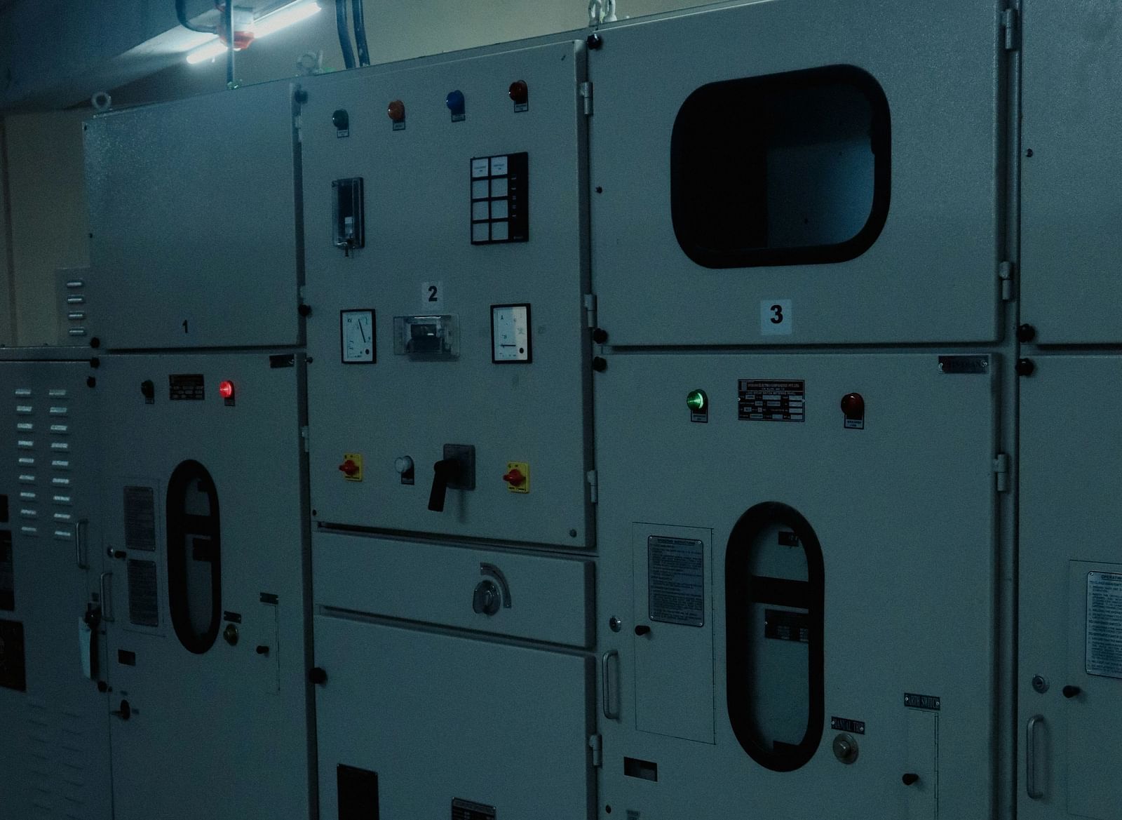 A row of industrial grey electrical panels with various gauges, switches, and indicator lights.