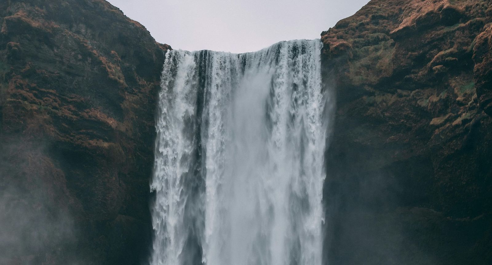 image of a waterfalls with a cloudy backdrop falling from the rocks fro a height