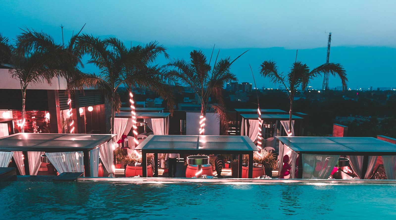 a view of a restaurant with an infinity pool beside and tents kept on the poolside - Hotel Park Elanza, Chennai