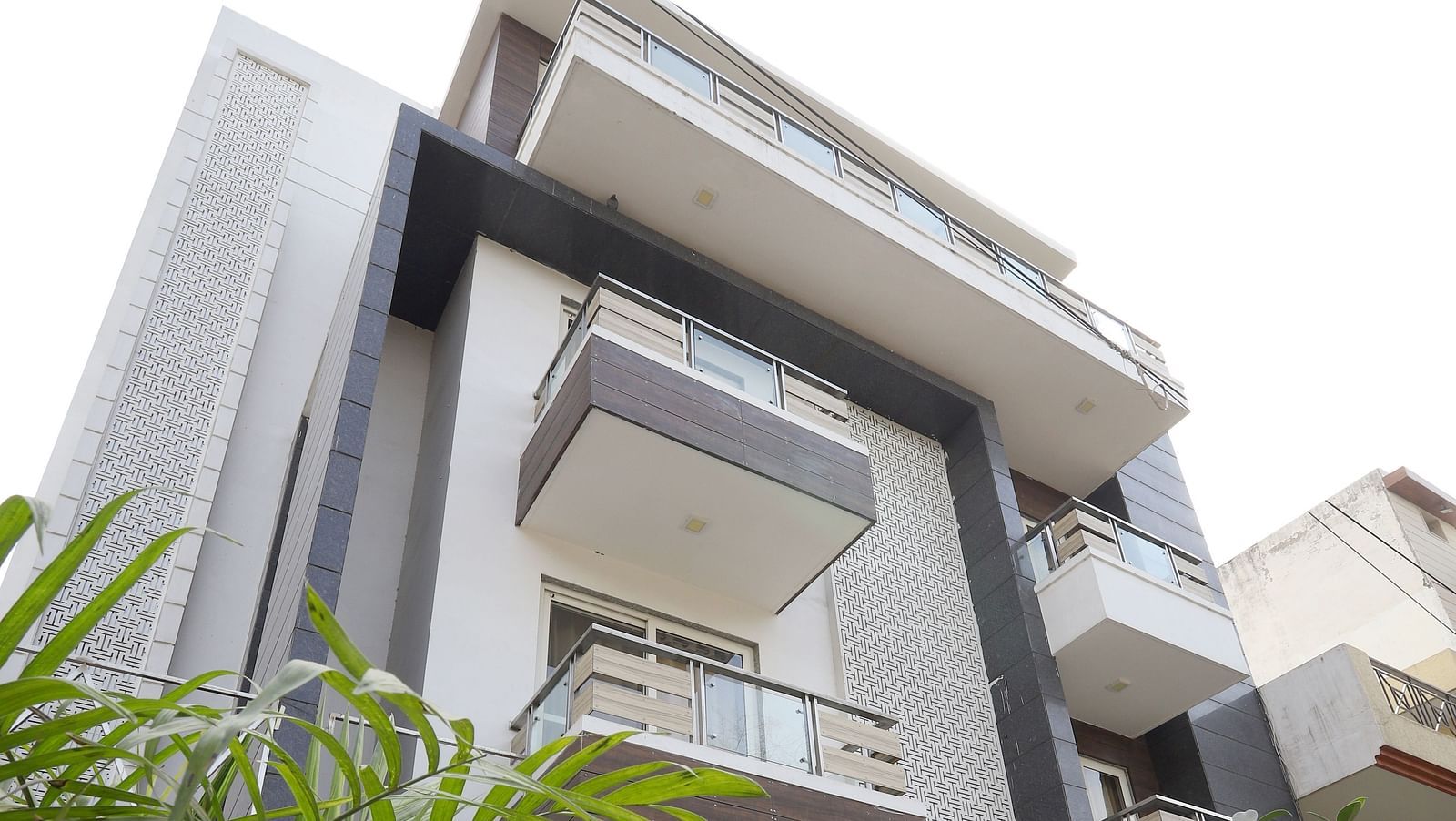 An exterior shot of a contemporary building with angular design and greenery visible in the foreground - Asian Suites Cyber Park, Gurgaon