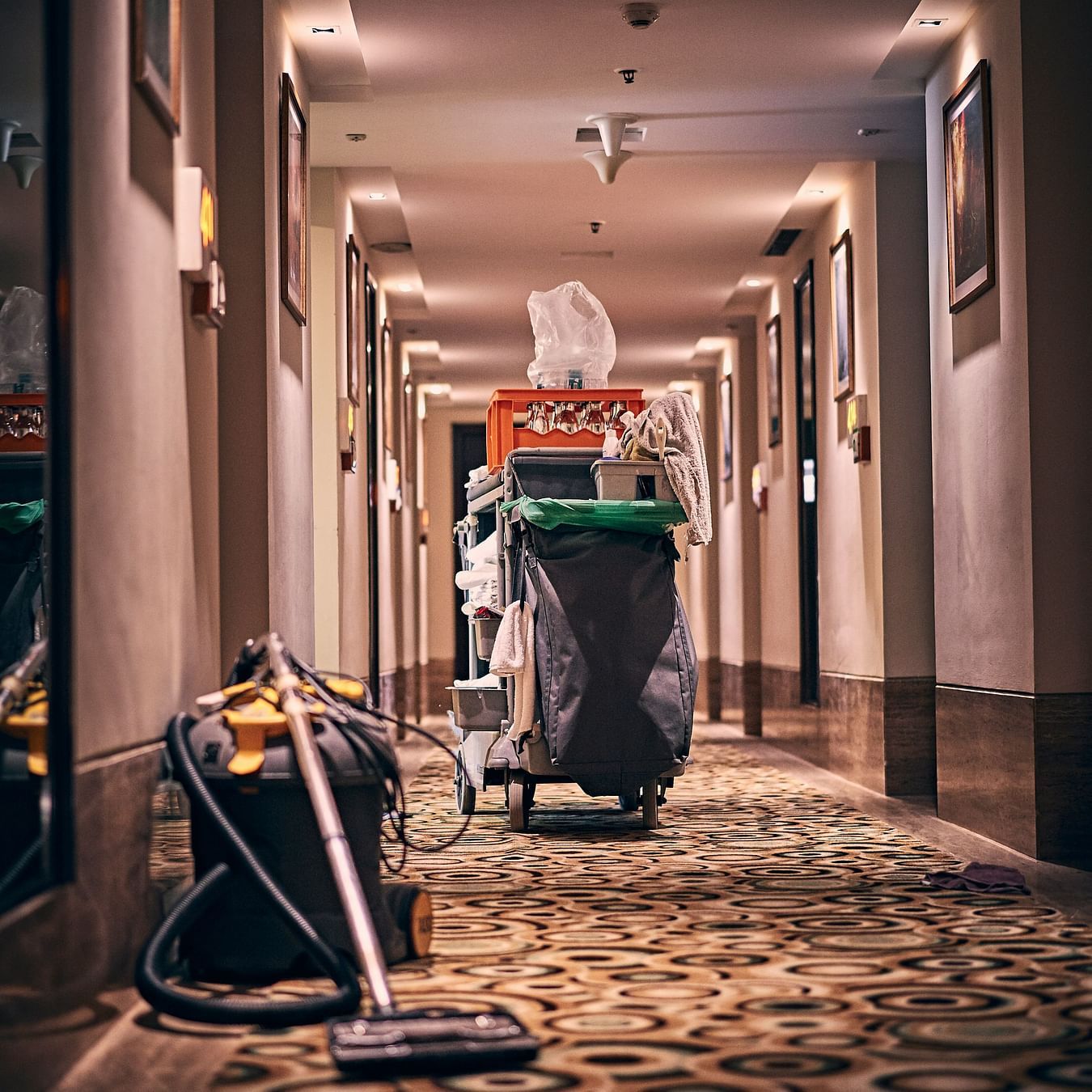 A housekeeping cart in a hotel corridor with patterned carpeting