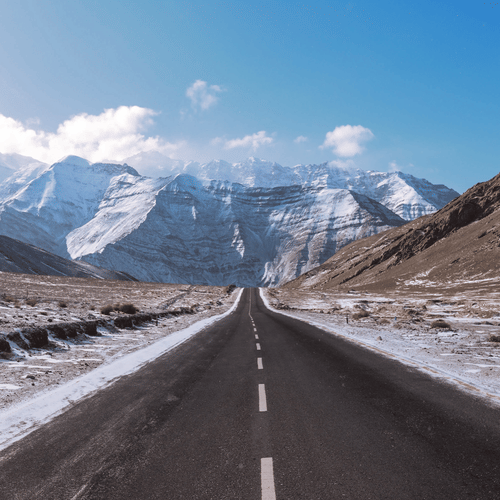 A view of a straight road leading towards majestic mountains.