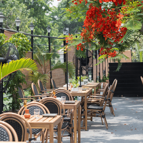 Outdoor seating with chairs under red flowers at Polo Floatel Kolkata.