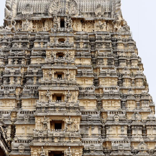 A view from below of a temple's facade with intricate art on the exterior of the roof in Tirupati.