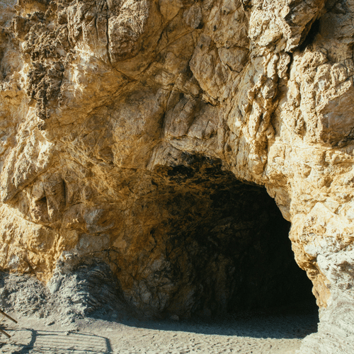 An overview of a cave entrance with a narrow opening and blue sky in the background. Sita Gufa timings is from 6:00 AM to 9:00 PM, and the entrance is as narrow as this.