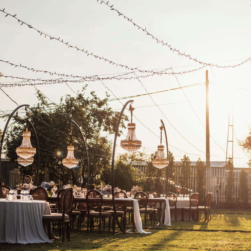 A garden area decorated for an event during the early evening hours with tables and chairs set.