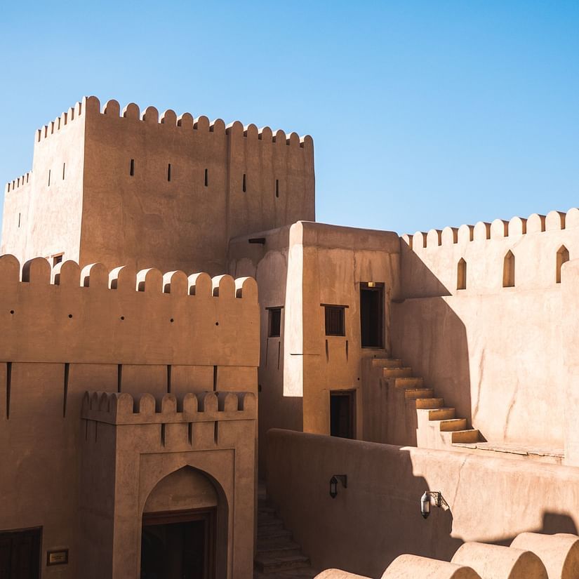 A traditional fortress with crenellated walls and arched doorways under a clear blue sky.
