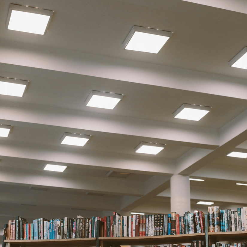 A vertical shot of a library bookshelf filled with books, with a ceiling visible above.